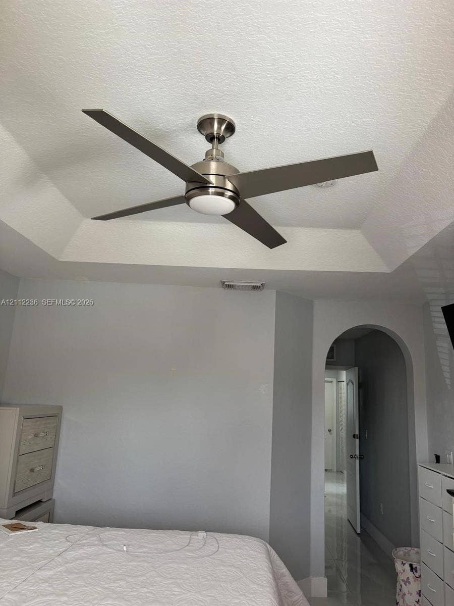 13946 SW 276th Street, #0, Homestead, FL 33032 Tray ceiling featuring a brushed nickel four-blade ceiling fan with an integrated light fixture and a structural arched doorway