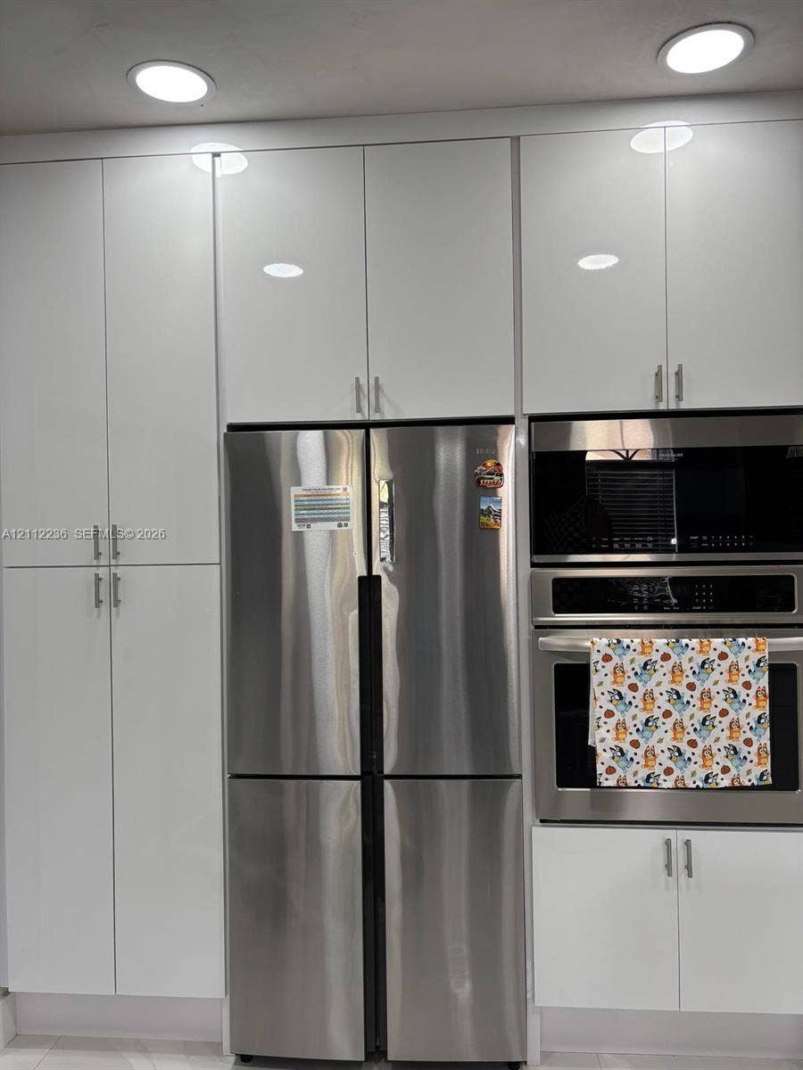 13946 SW 276th Street, #0, Homestead, FL 33032 Floor-to-ceiling white high-gloss cabinetry, stainless steel French-door refrigerator, built-in stainless steel microwave, integrated stainless steel oven, and recessed ceiling lighting