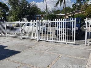 260 NW 40th Street, #S, Miami, Miami, FL 33127 White metal picket fencing with a sliding access gate, featuring a concrete paver driveway with gravel fill