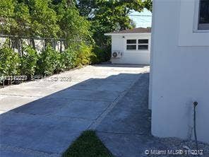 260 NW 40th Street, #S, Miami, Miami, FL 33127 Concrete driveway, white stucco exterior, detached structure with window, and chain-link perimeter fencing