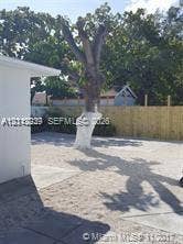 260 NW 40th Street, #S, Miami, Miami, FL 33127 Rear exterior featuring a stone-surfaced yard, wood fencing, and mature trees