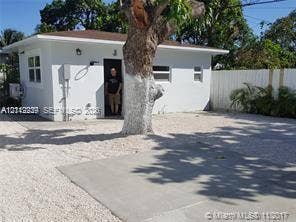 260 NW 40th Street, #S, Miami, Miami, FL 33127 Single-story exterior featuring white stucco siding, a concrete parking pad, gravel ground cover, and a white privacy fence