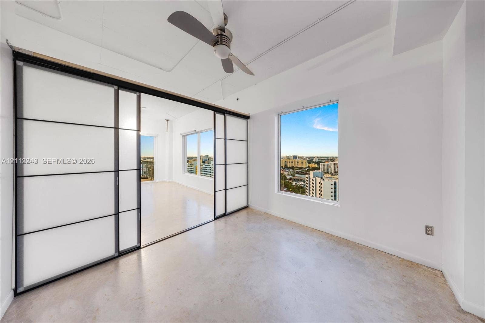 Interior space featuring polished concrete flooring, sliding frosted glass partitions with black frames, and an integrated ceiling fan