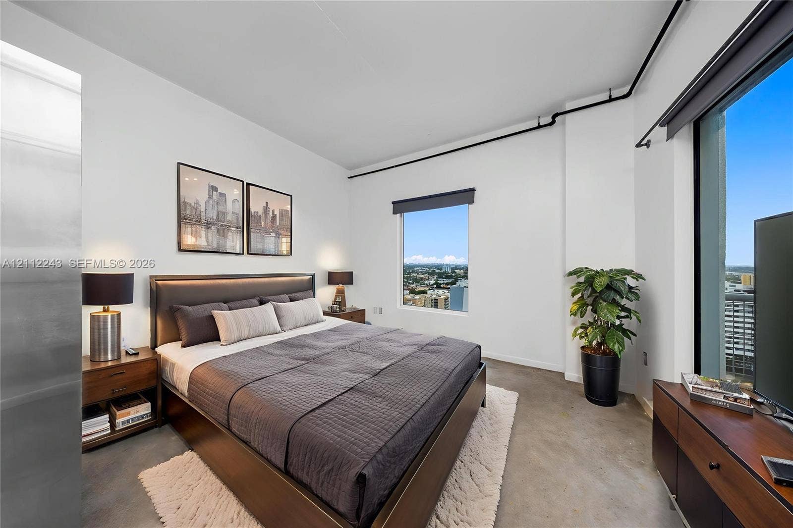 Polished concrete flooring, floor-to-ceiling window, exposed industrial-style conduit, and high-rise cityscape horizon