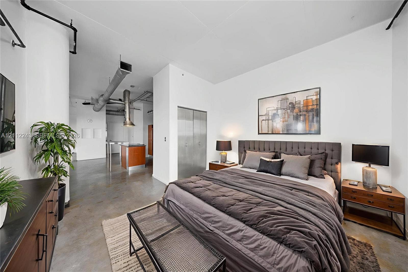 Industrial-style loft featuring exposed overhead ductwork, polished concrete flooring, soaring ceilings, and metal-clad closet doors