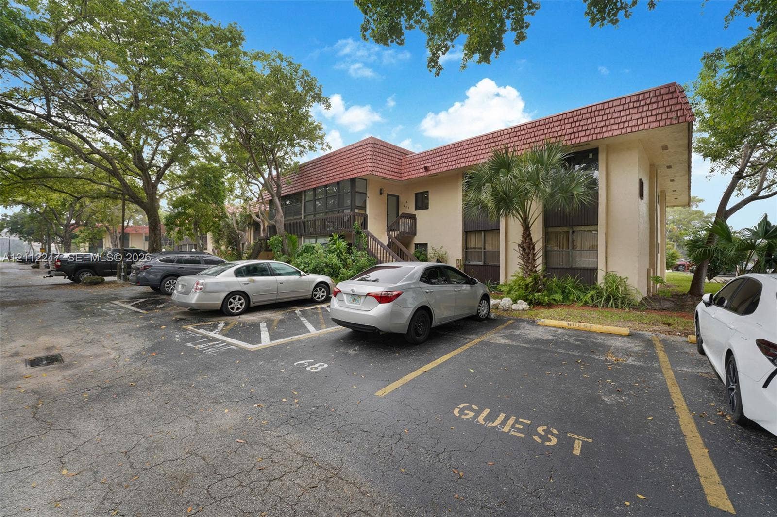 Two-story exterior featuring a clay tile roof, stucco facade, and designated on-site parking