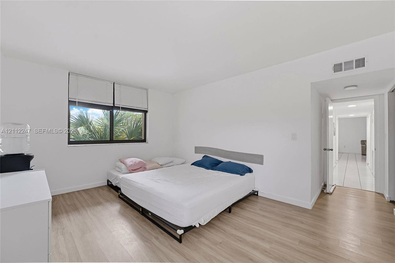 Room featuring wood-finish flooring, a neutral color palette, and a large window with blind treatments
