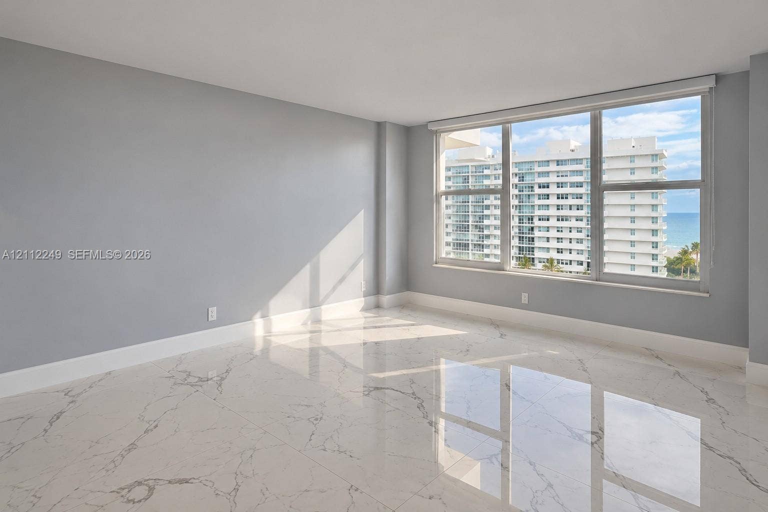 Large-format polished stone flooring with veining detail, expansive windows, and neutral interior paint palette