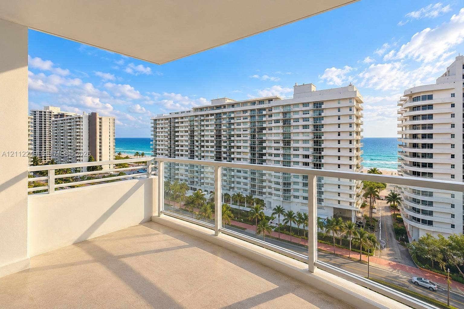 Covered balcony with a glass and metal railing overlooking the oceanfront and coastal skyline