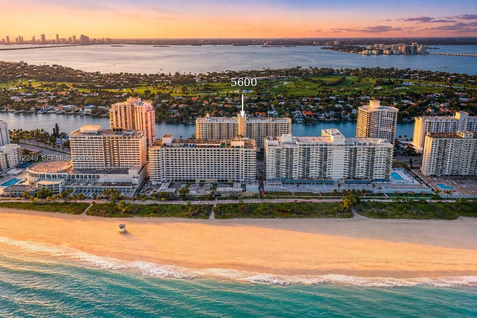 Aerial perspective of coastal high-rise building featuring immediate beach access, oceanfront positioning, and surrounding waterways