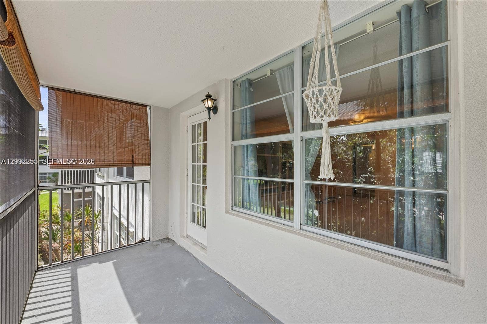 4025 N Federal Highway, #226C, Oakland Park, FL 33308 Covered balcony featuring metal railings, a full-lite glass panel door, exterior wall-mounted lighting, and neutral flooring