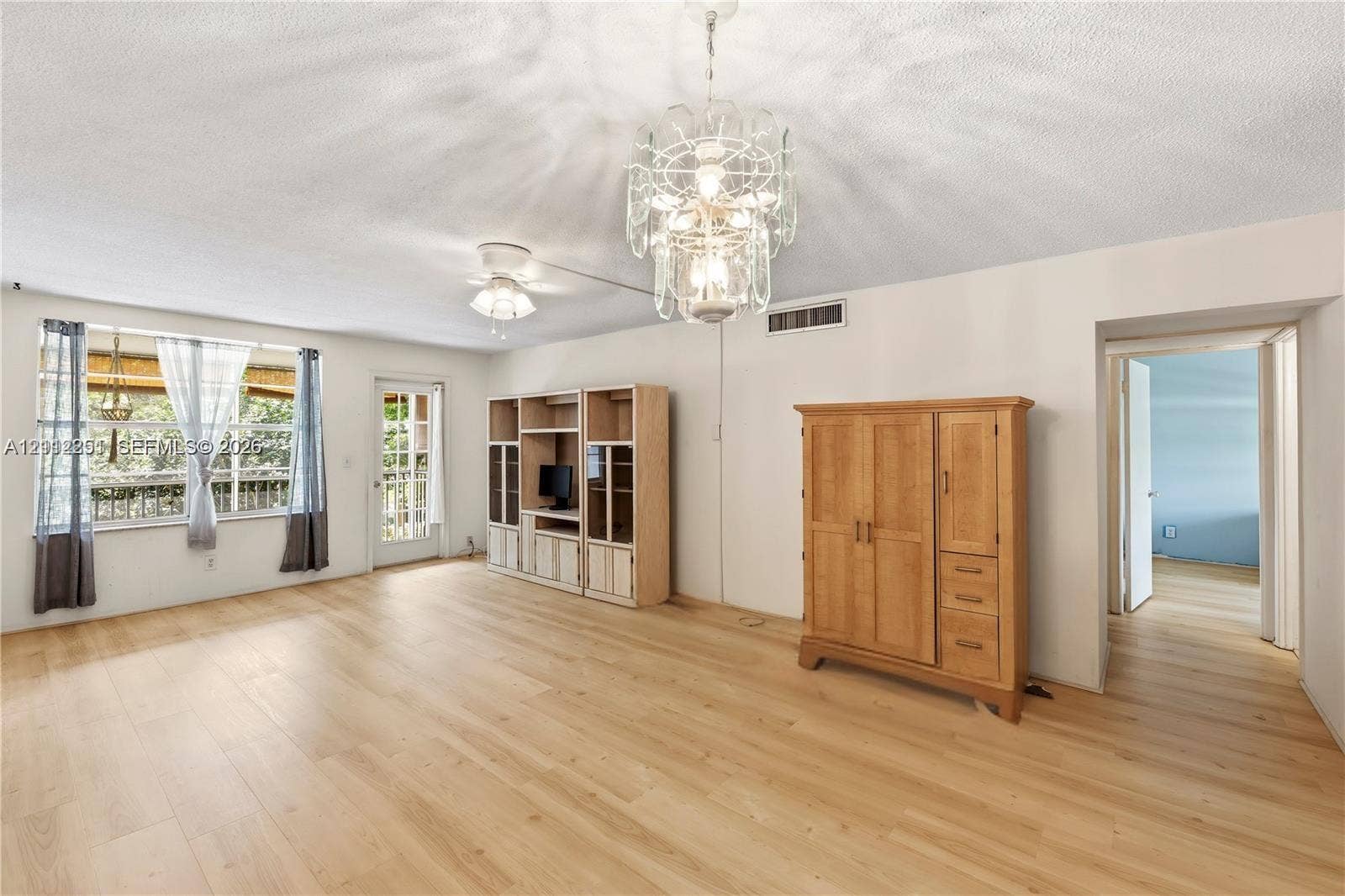 4025 N Federal Highway, #226C, Oakland Park, FL 33308 Open floor plan featuring wood-finish flooring, a multi-tiered crystal chandelier, a ceiling fan with integrated lighting, and built-in floor-to-ceiling cabinetry