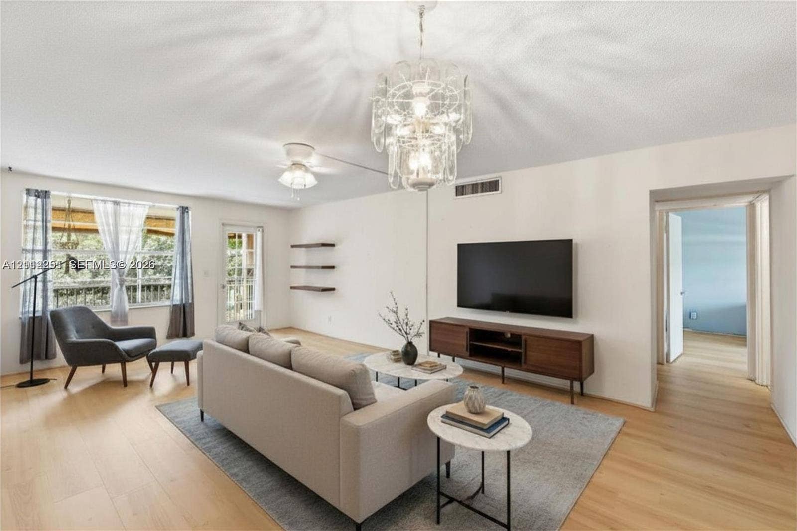4025 N Federal Highway, #226C, Oakland Park, FL 33308 Living area featuring wood-finish flooring, a decorative multi-tiered chandelier, and three built-in wall shelves
