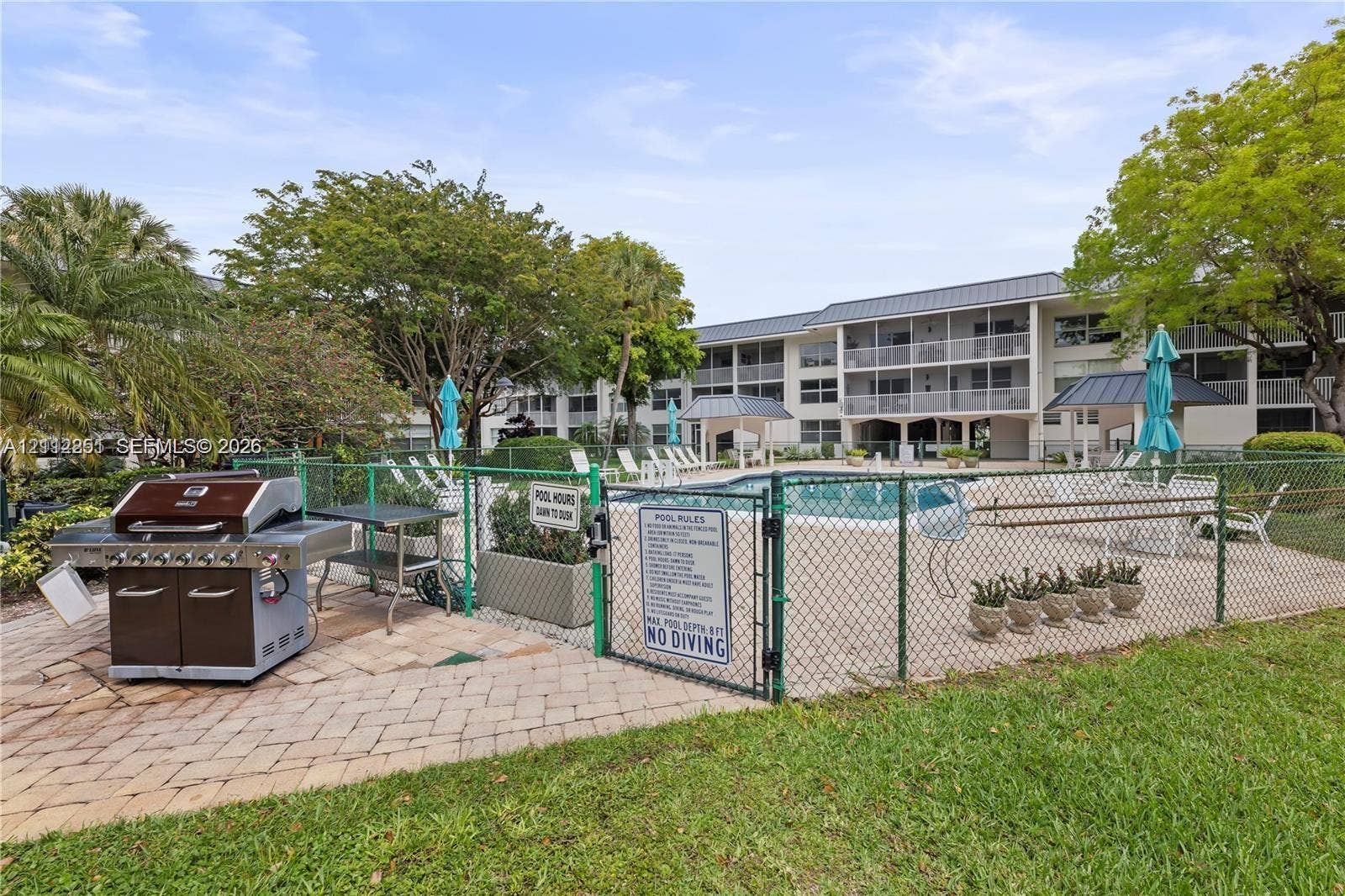 4025 N Federal Highway, #226C, Oakland Park, FL 33308 Community swimming pool with brick paver surround, built-in stainless steel outdoor grill station, and mature landscaping