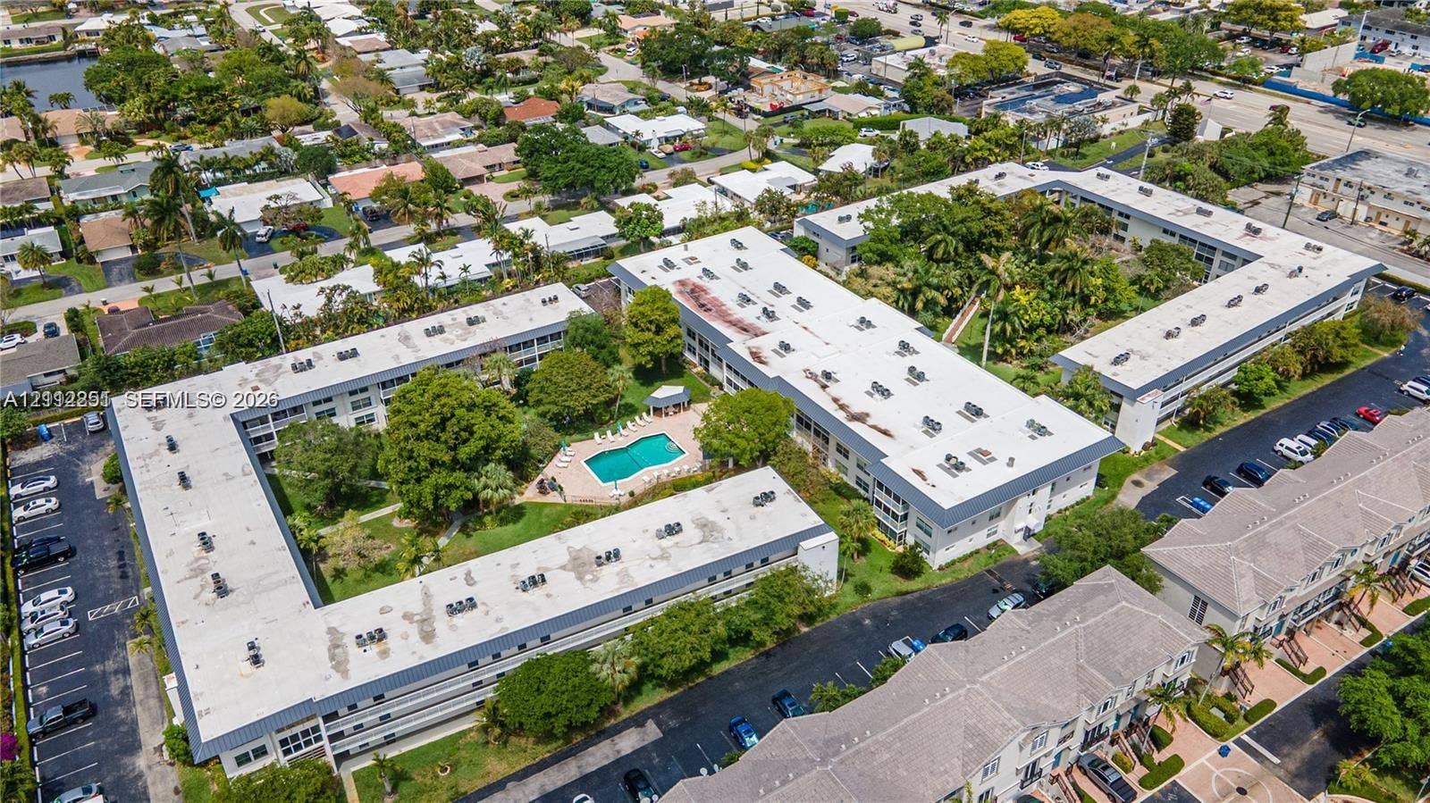 4025 N Federal Highway, #226C, Oakland Park, FL 33308 Aerial perspective of the property featuring a central swimming pool, paved surface parking areas, and mature landscaping