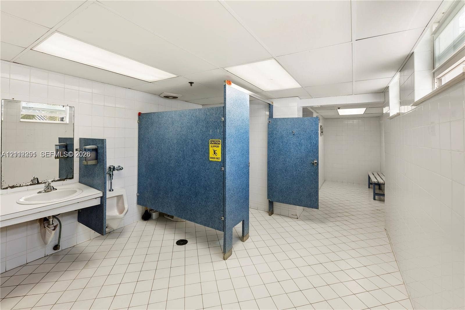 4025 N Federal Highway, #226C, Oakland Park, FL 33308 Restroom featuring ceramic tile walls and flooring, drop ceiling with recessed lighting, blue privacy partitions, wall-mounted sink, and built-in bench seating
