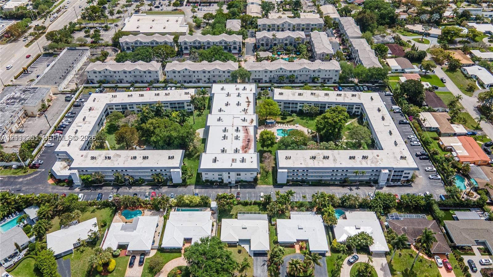 4025 N Federal Highway, #226C, Oakland Park, FL 33308 Aerial perspective of a multi-building residential complex featuring a central courtyard, landscaped grounds, swimming pool, and dedicated asphalt parking areas