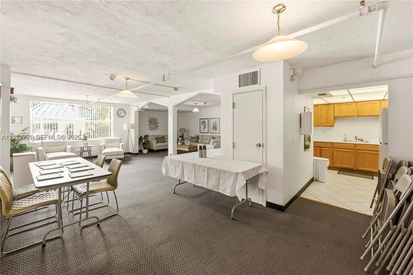 4025 N Federal Highway, #226C, Oakland Park, FL 33308 Open-concept interior featuring large windows, neutral carpeting, recessed and pendant lighting, and a kitchen area with wood-finish cabinetry