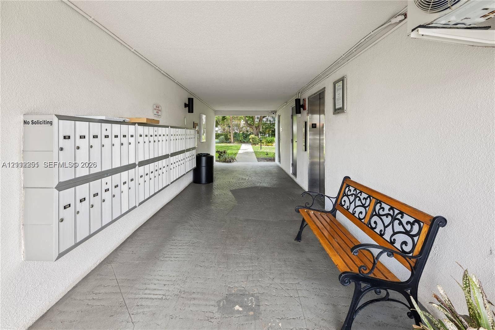 4025 N Federal Highway, #226C, Oakland Park, FL 33308 Covered breezeway featuring a wall-mounted communal mailbox bank, metallic elevator doors, and textured wall finishes