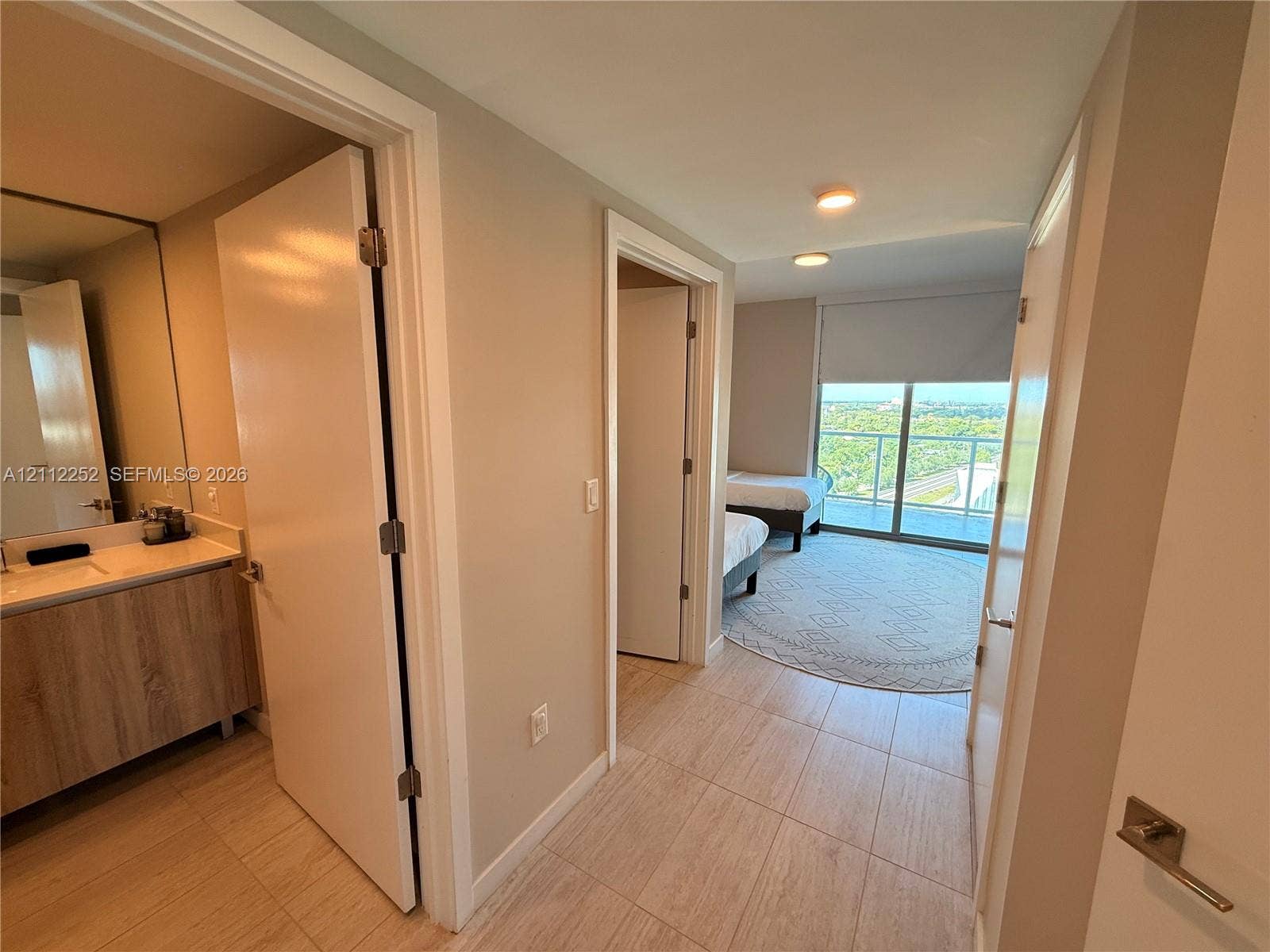 3900 Biscayne Boulevard, #N-1113, Miami, FL 33137 Hallway featuring tile flooring, light wood-finish vanity with countertop, and sliding glass door with balcony access