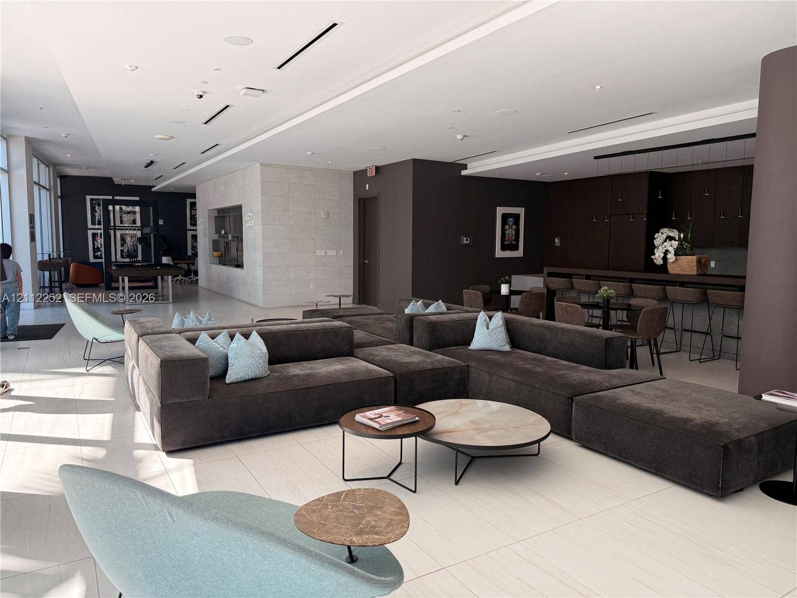 3900 Biscayne Boulevard, #N-1113, Miami, FL 33137 Open-concept interior featuring large-format tile flooring, recessed ceiling lighting, stone-textured accent wall, and a built-in dark wood cabinetry bar