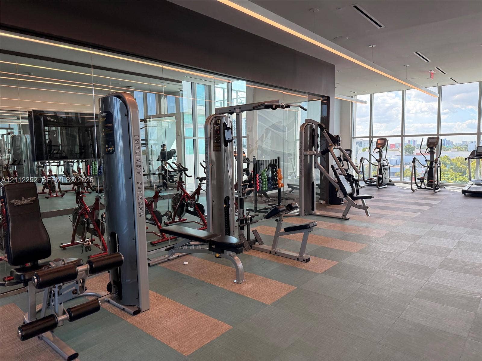 3900 Biscayne Boulevard, #N-1113, Miami, FL 33137 Fitness center featuring floor-to-ceiling windows, mirrored walls, recessed linear lighting, and large-format tiled flooring