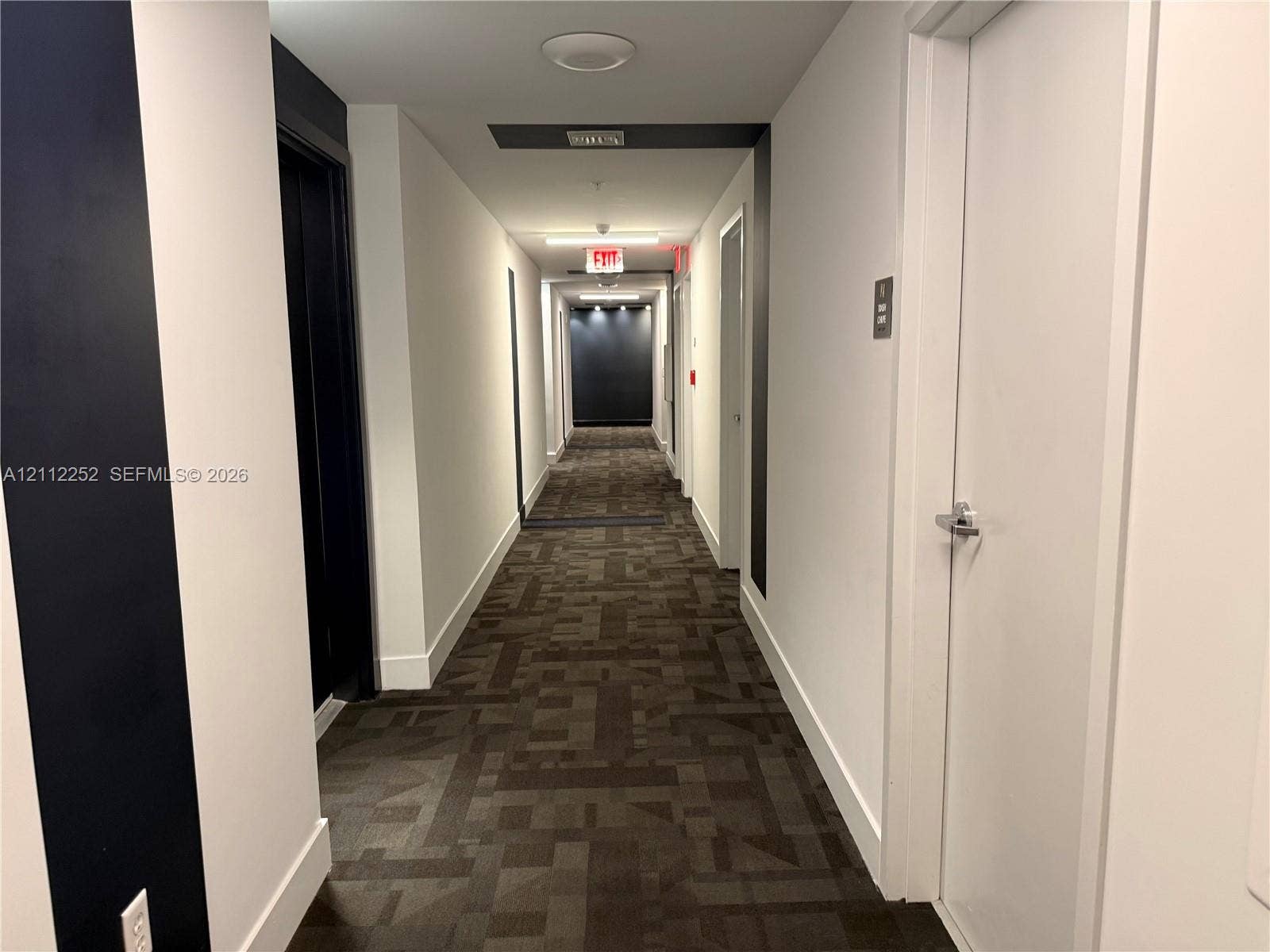 3900 Biscayne Boulevard, #N-1113, Miami, FL 33137 Hallway featuring patterned carpet, high-contrast dark accent walls, white interior doors with satin nickel hardware, and recessed ceiling lighting