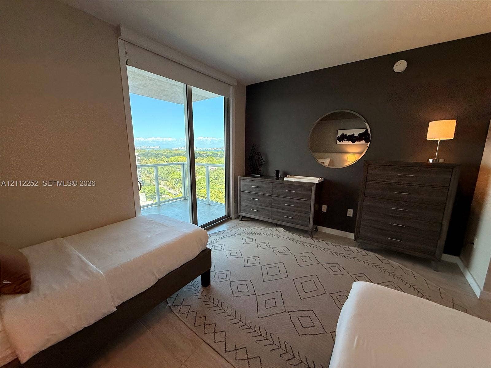 3900 Biscayne Boulevard, #N-1113, Miami, FL 33137 Floor-to-ceiling glass sliding door, balcony with glass railing, wood-finish flooring, and accent wall