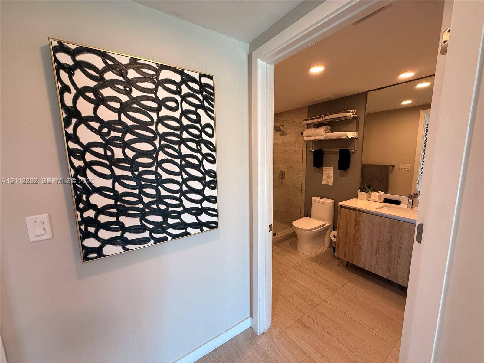 3900 Biscayne Boulevard, #N-1113, Miami, FL 33137 Bathroom featuring a floating vanity with wood-finish cabinetry, a large wall-mounted mirror, recessed lighting, and a walk-in shower with neutral tile surround