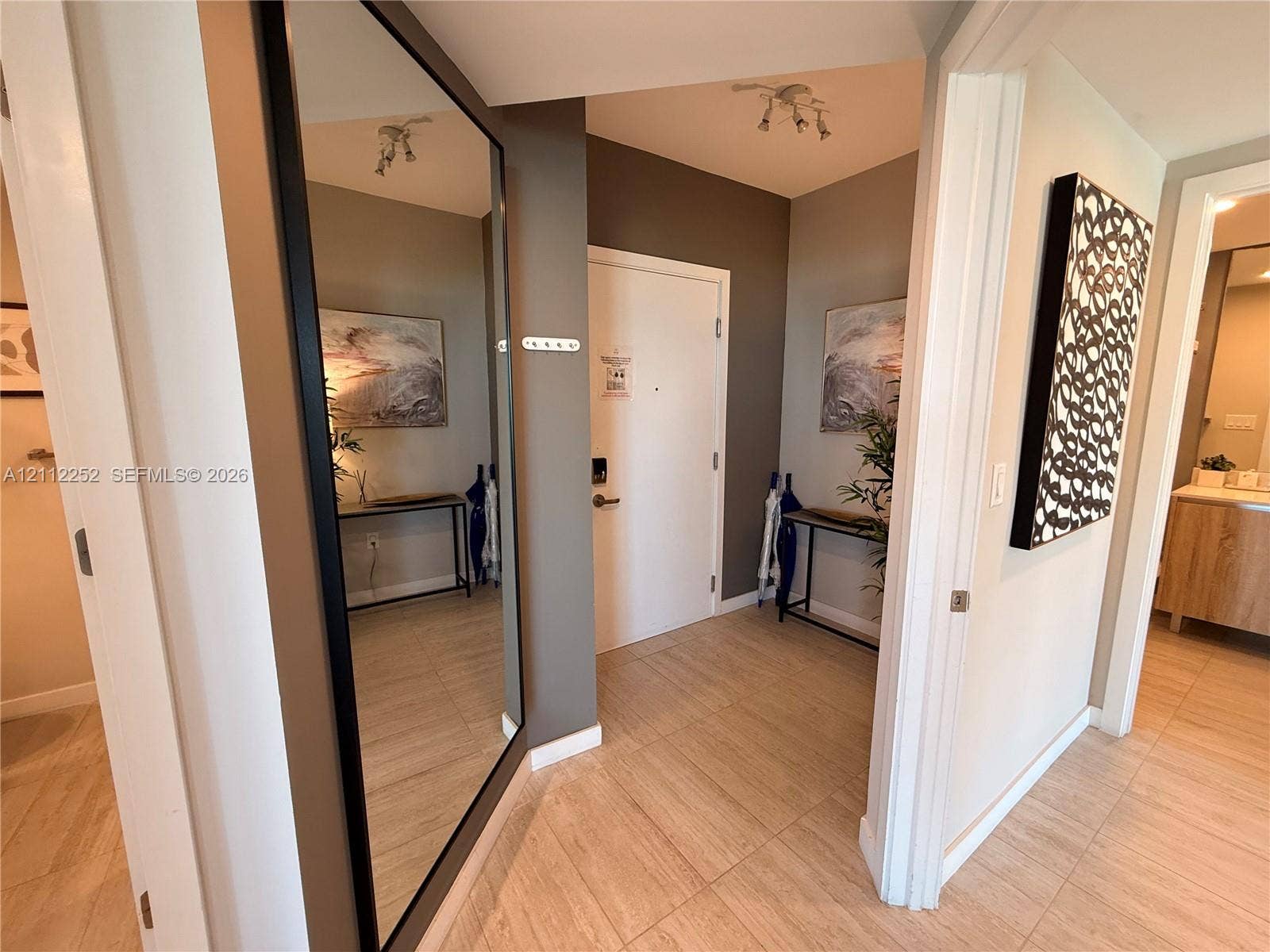 3900 Biscayne Boulevard, #N-1113, Miami, FL 33137 Entryway featuring large-format tile flooring, a floor-to-ceiling wall-mounted mirror with a black frame, and multi-directional overhead track lighting