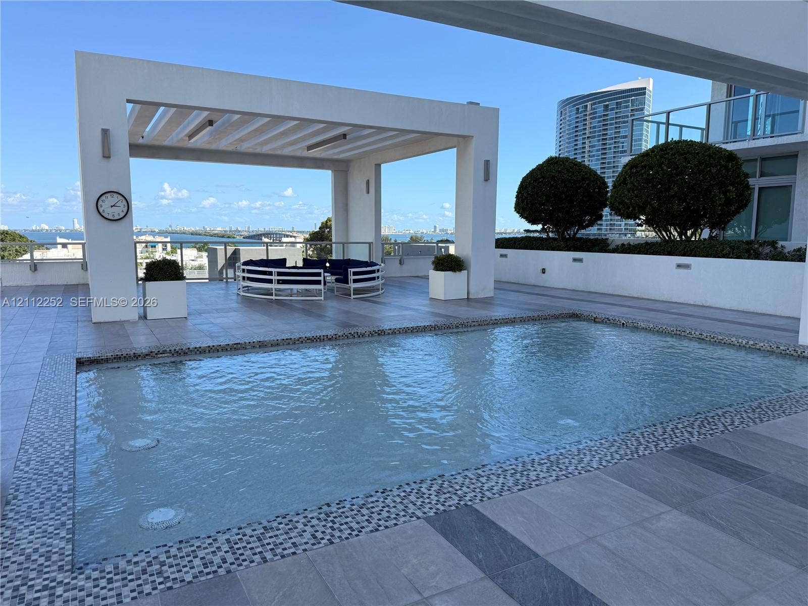 3900 Biscayne Boulevard, #N-1113, Miami, FL 33137 Terrace featuring a swimming pool with decorative mosaic tile trim, a structural pergola, large-format tile flooring, and integrated wall lighting