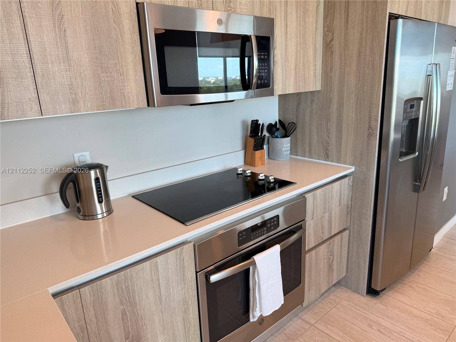 3900 Biscayne Boulevard, #N-1113, Miami, FL 33137 Kitchen featuring flat-panel wood-finish cabinetry, quartz countertops, stainless steel appliances, a smooth-surface electric cooktop, and built-in microwave