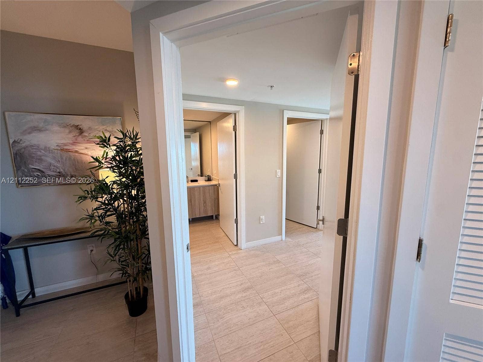 3900 Biscayne Boulevard, #N-1113, Miami, FL 33137 Ceramic tile flooring, white-finished interior doors with brushed metal hardware, and louvered closet doors