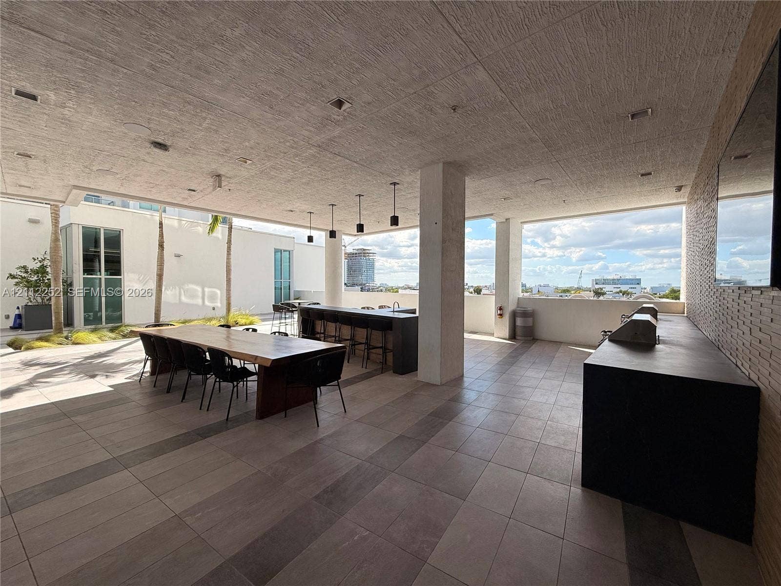 3900 Biscayne Boulevard, #N-1113, Miami, FL 33137 Covered outdoor terrace featuring large-format tile flooring, a built-in outdoor kitchen with a dark countertop, recessed ceiling lighting, and pendant fixtures