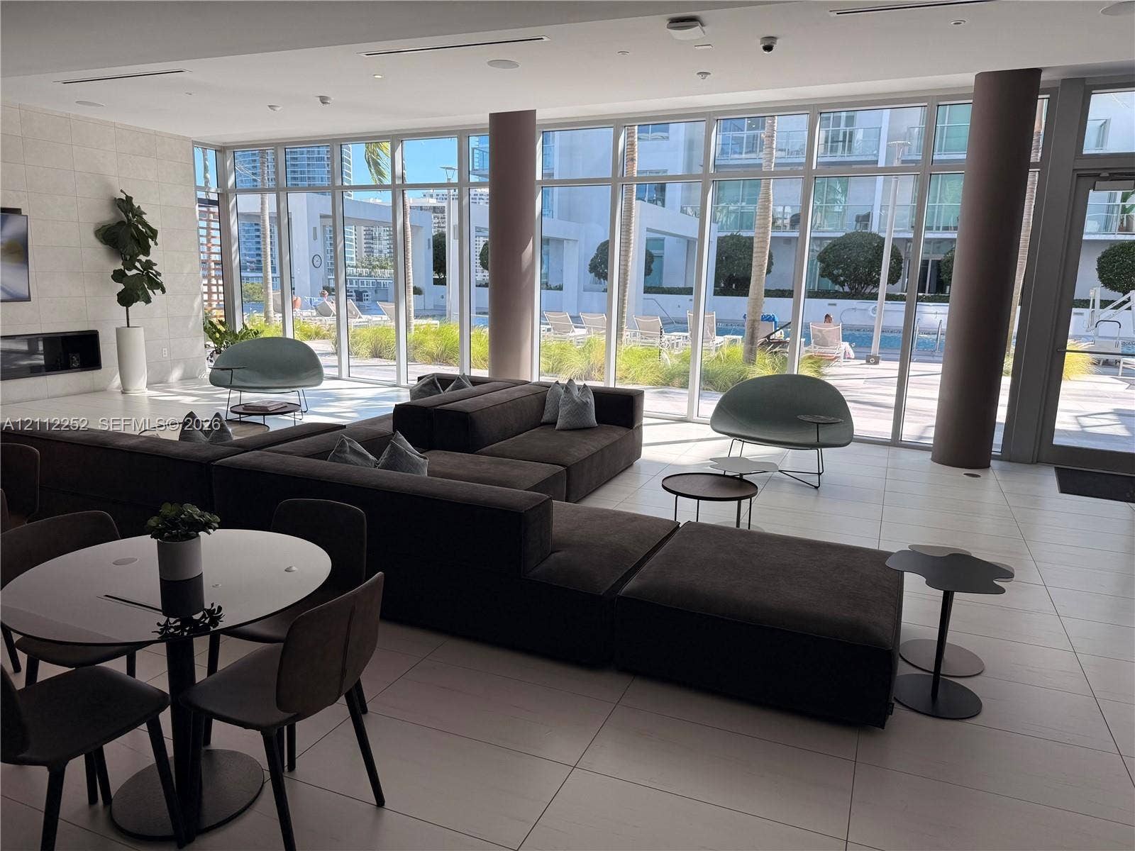 3900 Biscayne Boulevard, #N-1113, Miami, FL 33137 Common area featuring floor-to-ceiling windows, large-format tile flooring, built-in horizontal fireplace, and cylindrical support columns