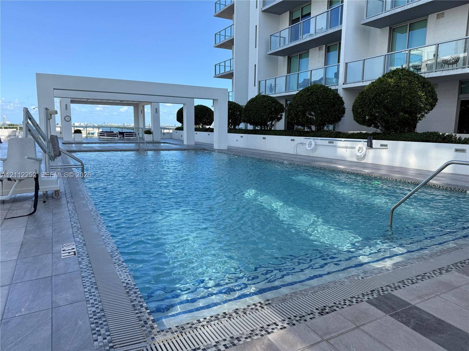 3900 Biscayne Boulevard, #N-1113, Miami, FL 33137 Outdoor swimming pool featuring a tiled deck, covered pavilion, manicured landscaping, and stainless steel handrails