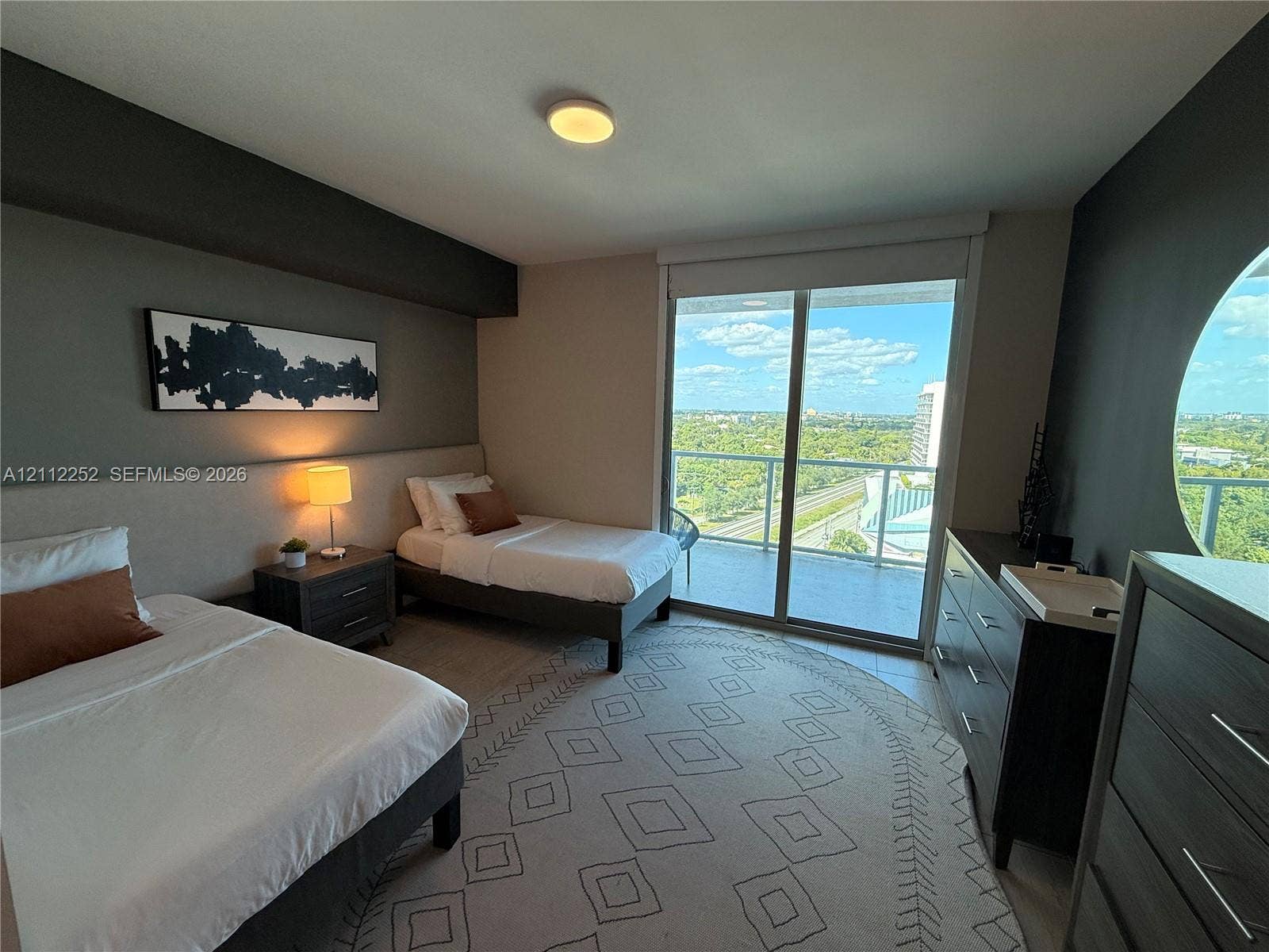 3900 Biscayne Boulevard, #N-1113, Miami, FL 33137 Sliding glass doors opening to a private balcony, large circular window, and neutral wall-finish flooring