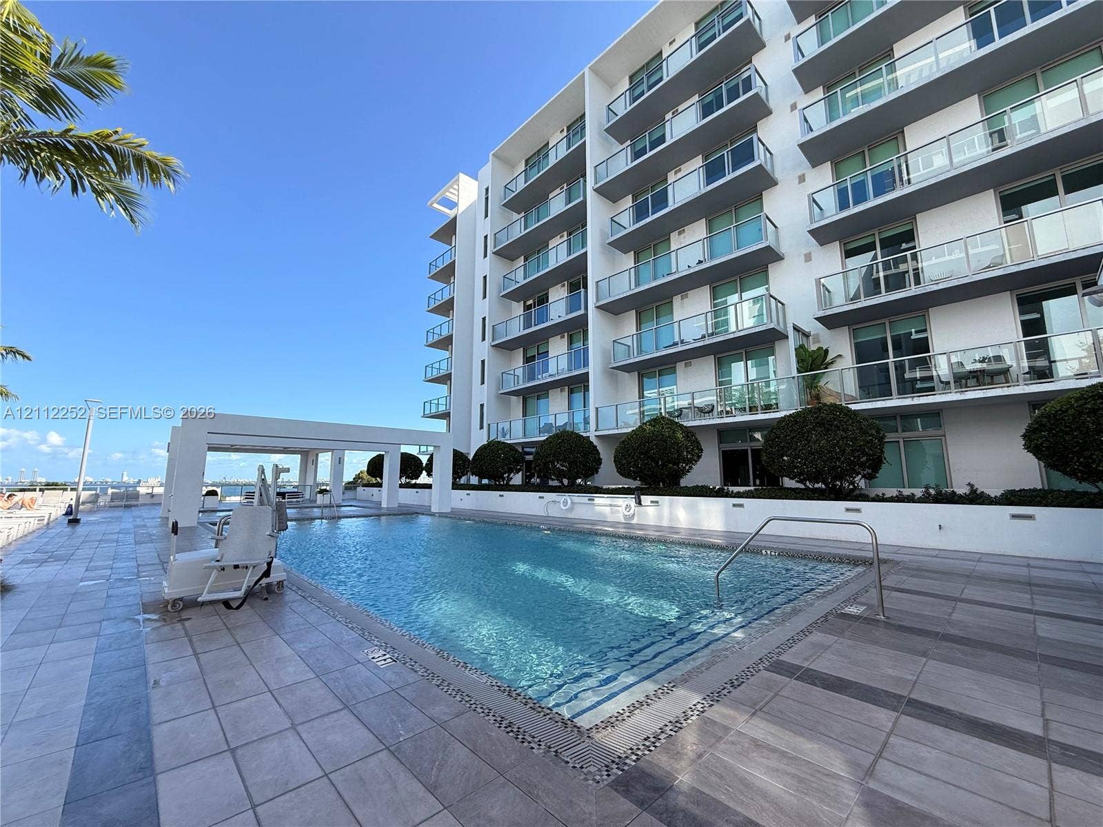 3900 Biscayne Boulevard, #N-1113, Miami, FL 33137 In-ground swimming pool with stone tiling, poolside cabana, paved terrace, and multi-story building exterior with glass-railed balconies