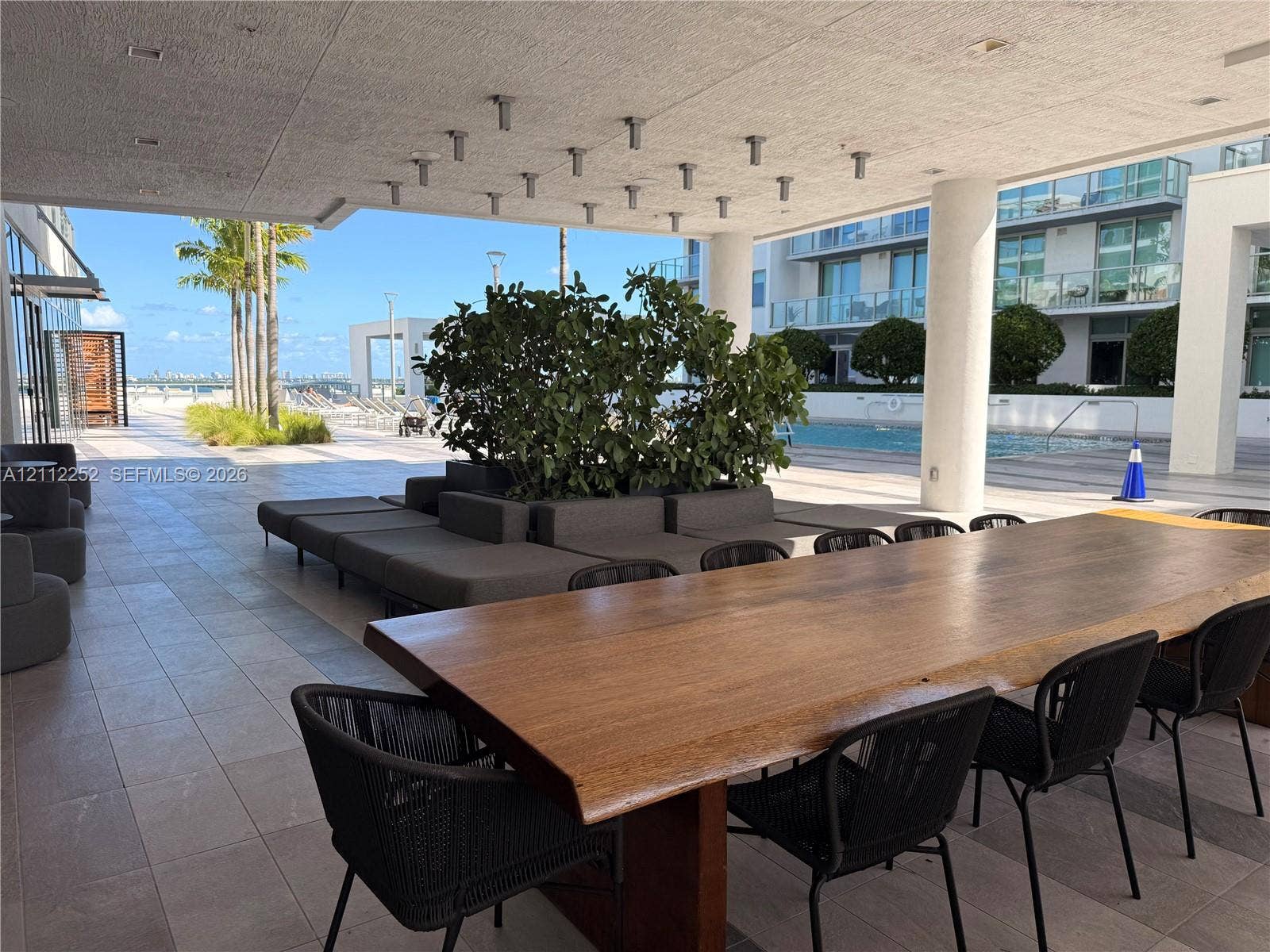 3900 Biscayne Boulevard, #N-1113, Miami, FL 33137 Covered outdoor terrace featuring large-format tile flooring, integrated ceiling lighting, structural columns, and direct access to a communal pool area
