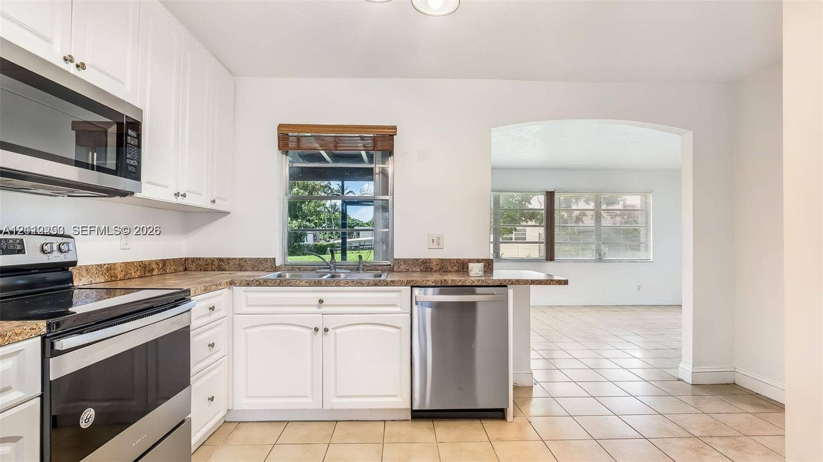 500 NW 96th Terrace, Pembroke Pines, FL 33024 Kitchen featuring white cabinetry, stainless steel appliances, patterned laminate countertops, a double-basin sink, and tile flooring