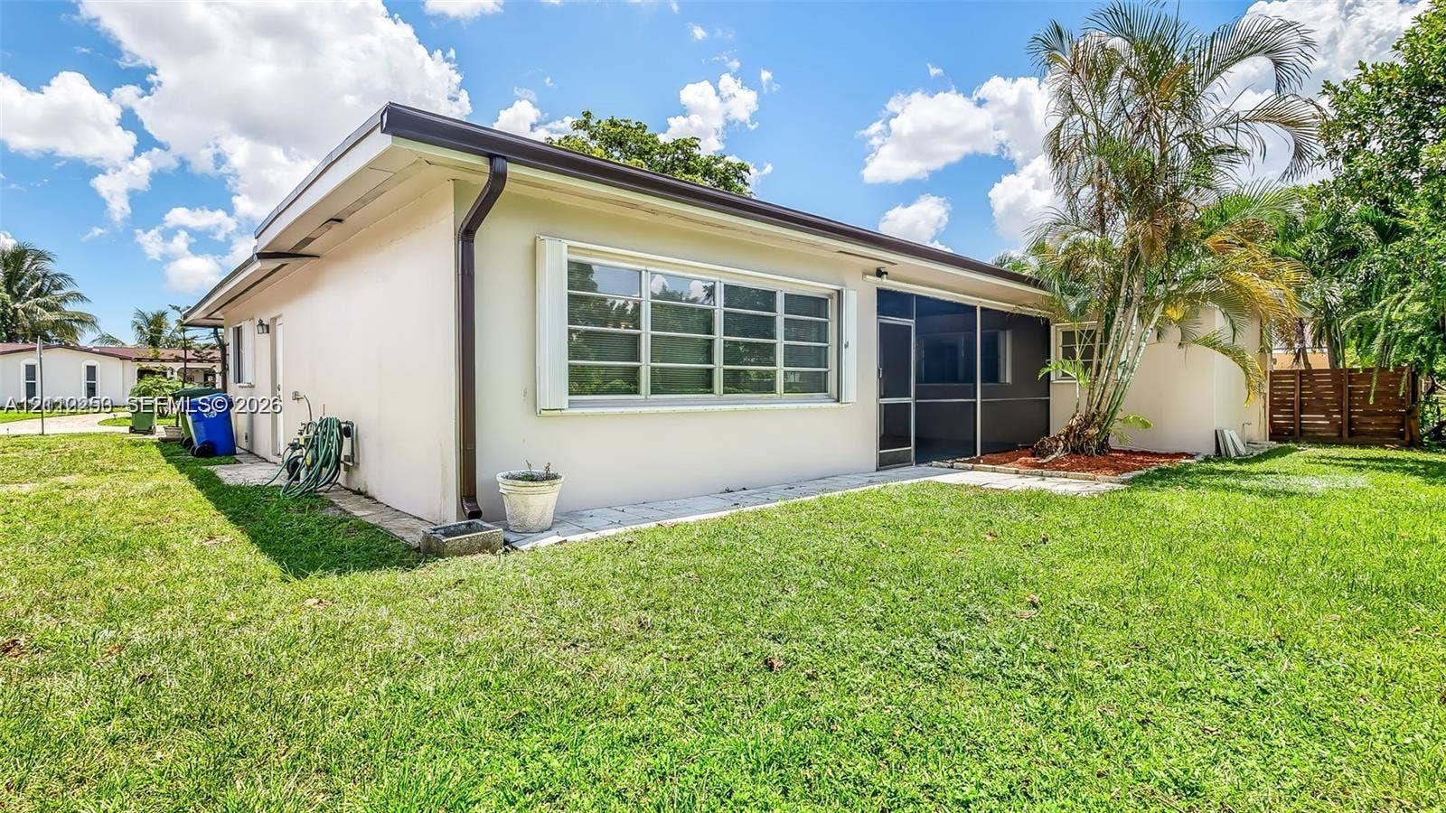 500 NW 96th Terrace, Pembroke Pines, FL 33024 Exterior elevation featuring a stucco finish, large multi-pane windows, a screened-in enclosure, and a manicured lawn