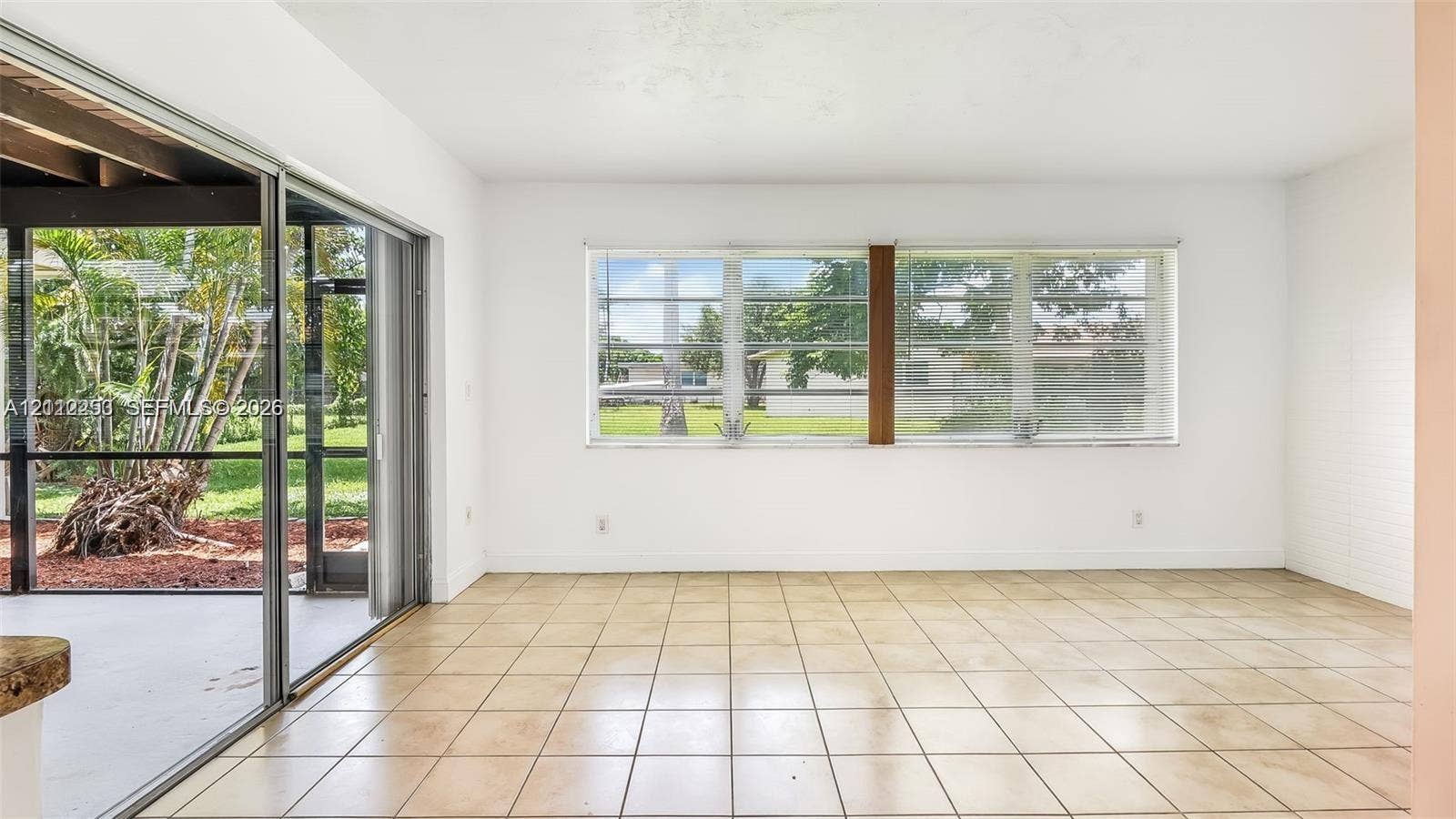 500 NW 96th Terrace, Pembroke Pines, FL 33024 Interior space featuring large-format ceramic tile flooring, expansive horizontal sliding windows, and a set of glass sliding doors providing external access