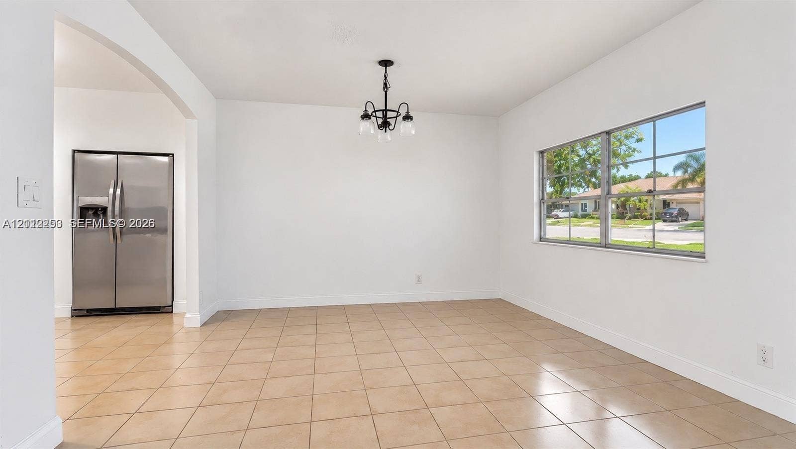 500 NW 96th Terrace, Pembroke Pines, FL 33024 Open interior featuring neutral tile flooring, a multi-pane window, a decorative black metal chandelier, and a stainless steel side-by-side refrigerator