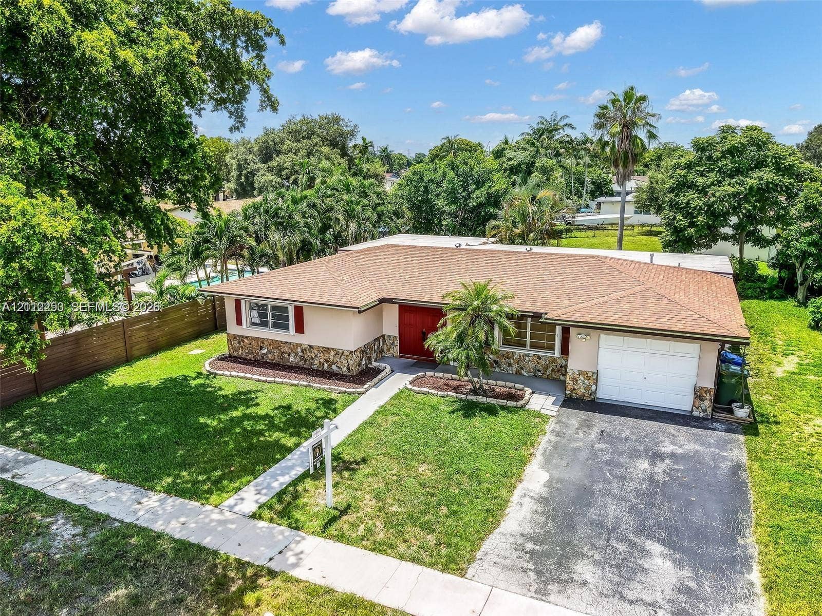 500 NW 96th Terrace, Pembroke Pines, FL 33024 Single-story residence featuring a stone veneer lower facade, an attached one-car garage, and a hip roofline