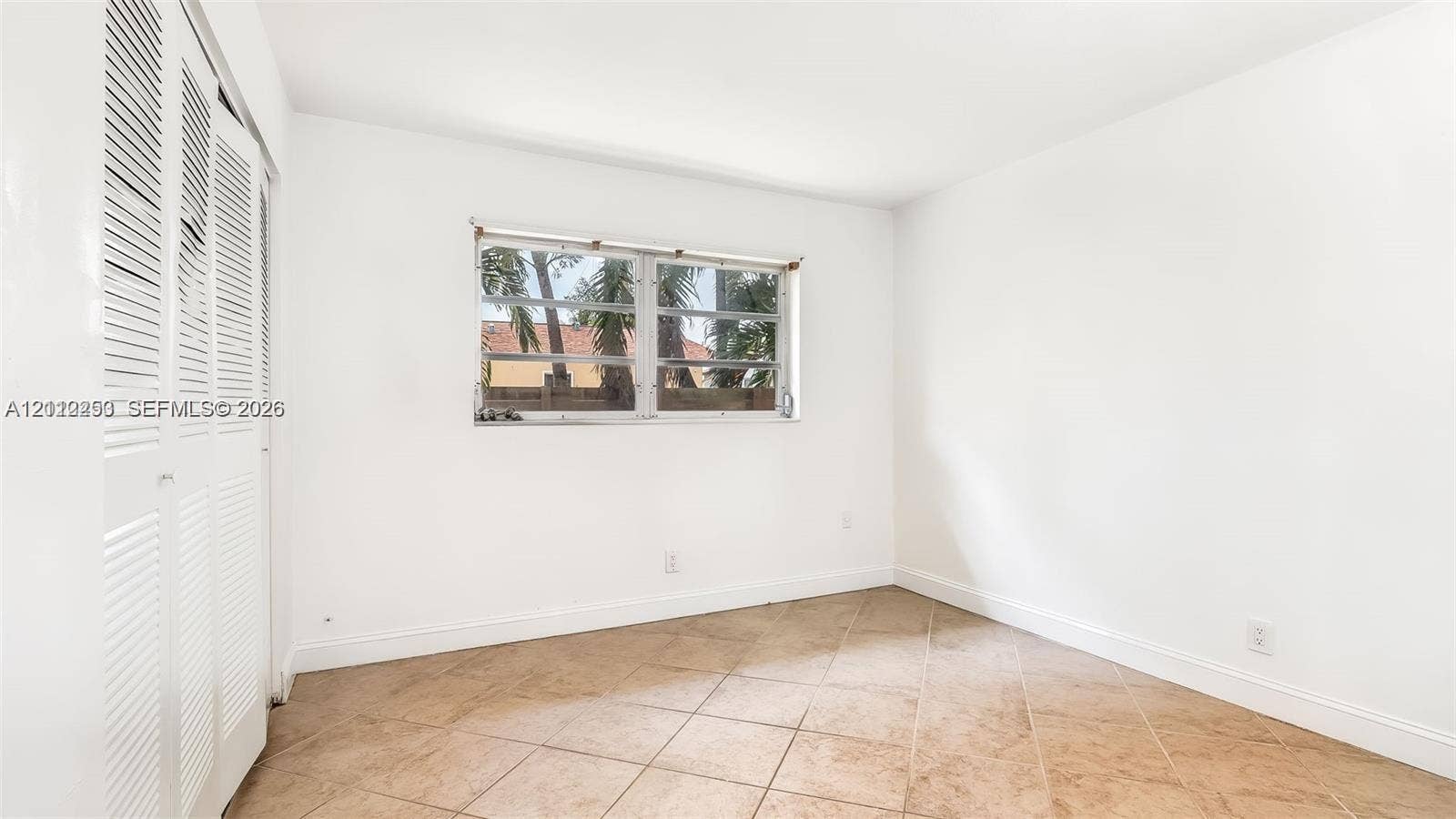 500 NW 96th Terrace, Pembroke Pines, FL 33024 Neutral-toned tile flooring, white walls, and built-in louvered-door closet