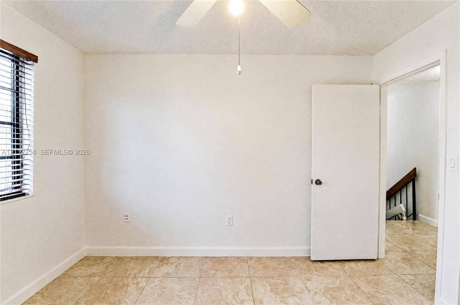 Interior space featuring tile flooring, a white ceiling fan with integrated lighting, and a single-pane window with horizontal blinds