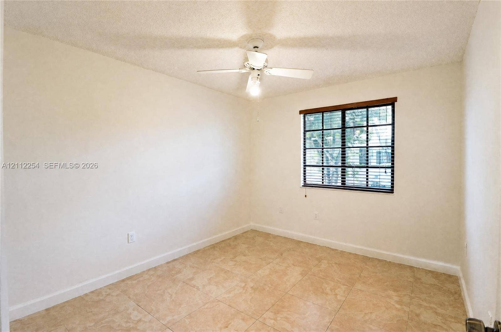 Room featuring neutral wall finishes, tile flooring, a grid-pattern window with dark frames, and a ceiling-mounted fan with integrated lighting