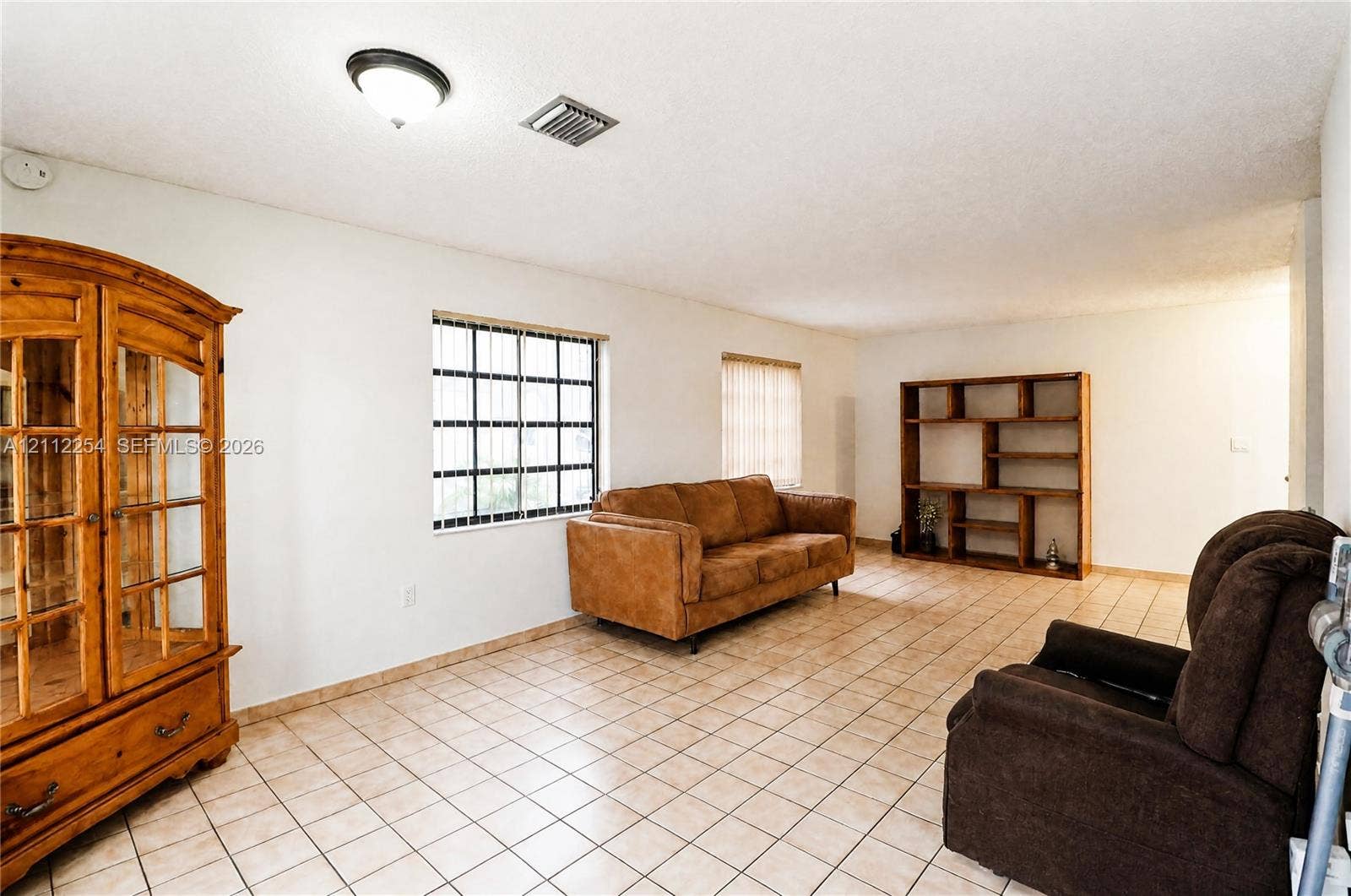 Interior space featuring neutral-toned tile flooring, recessed window grids, and built-in wooden shelving