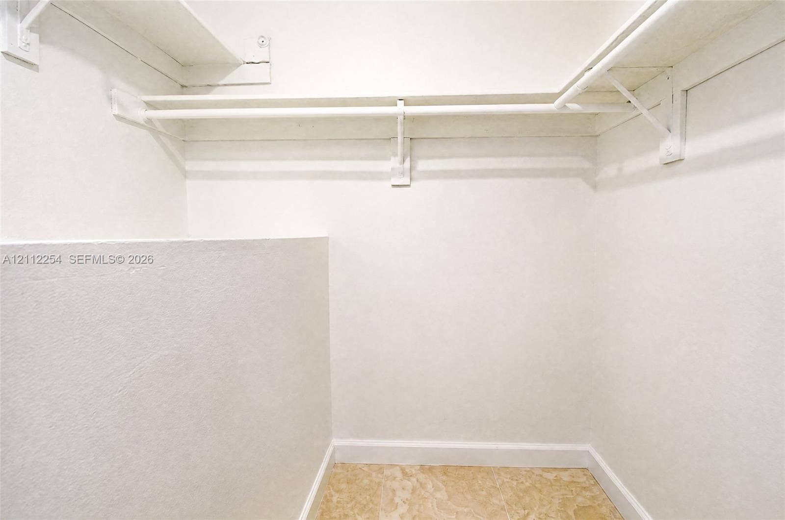 Storage area featuring tiered shelving, integrated hanging rods, and stone-finish flooring