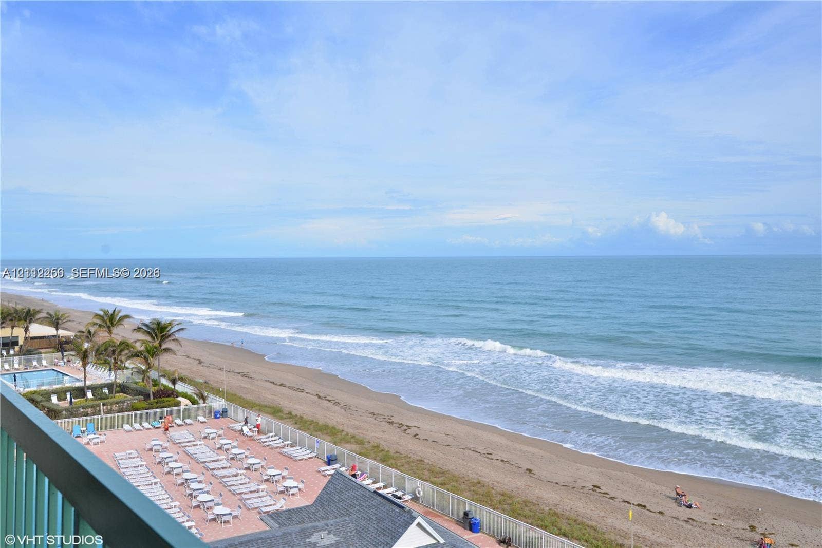 9900 S Ocean Drive, #601, Jensen Beach, FL 34957 Direct oceanfront perspective featuring a paved sun deck, swimming pool, perimeter fencing, and sand beach access